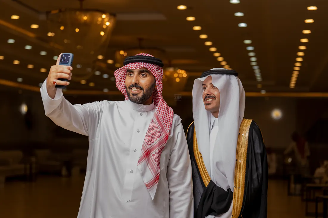 رجلان يلتقطان صورة سيلفي ضاحكين في قاعة الزفاف